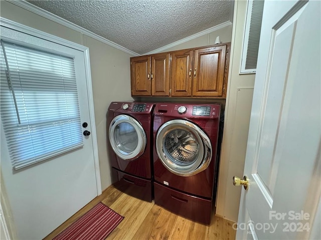 washroom featuring washing machine and clothes dryer, light hardwood / wood-style floors, a textured ceiling, and ornamental molding