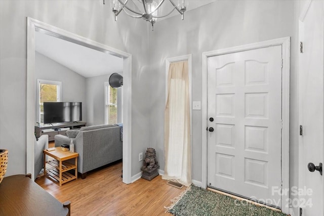 foyer featuring a notable chandelier, light hardwood / wood-style floors, and lofted ceiling