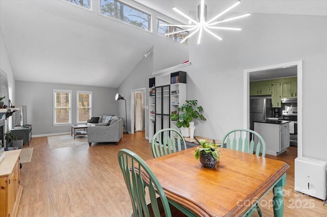 dining room with an inviting chandelier, high vaulted ceiling, and light wood-type flooring