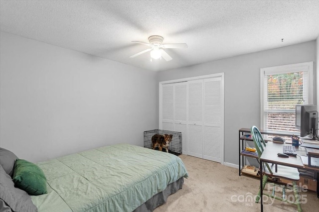 carpeted bedroom featuring ceiling fan, a closet, and a textured ceiling