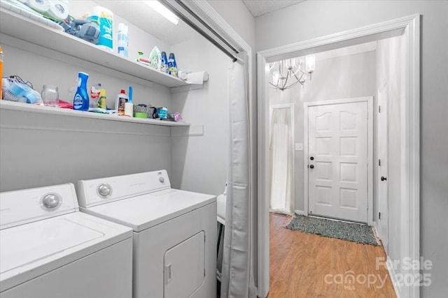 laundry room featuring washing machine and dryer, light hardwood / wood-style flooring, and a notable chandelier