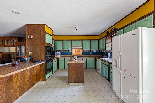 kitchen with butcher block counters, green cabinets, black appliances, and a textured ceiling