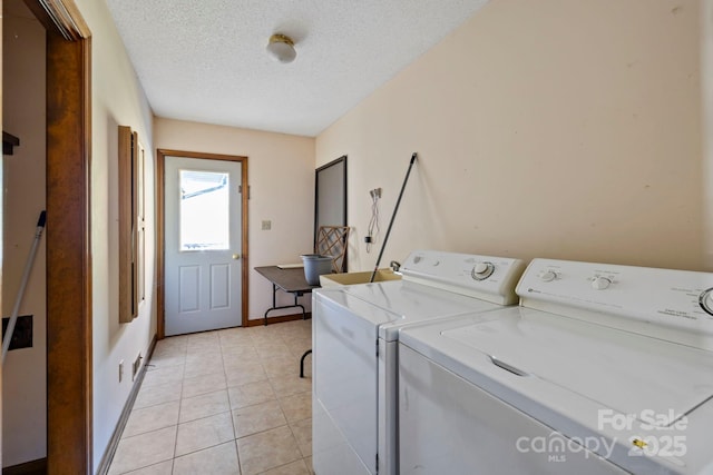 laundry area with washing machine and dryer, light tile patterned flooring, and a textured ceiling