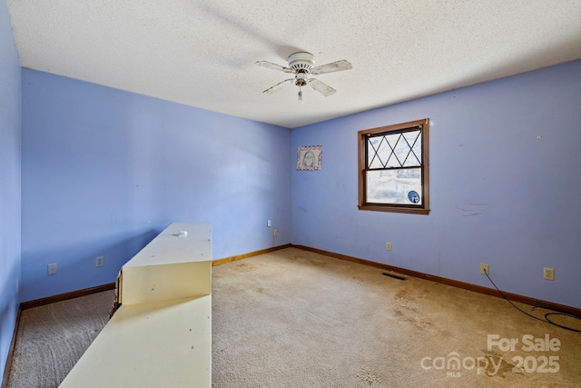 unfurnished room featuring a textured ceiling, carpet floors, and ceiling fan