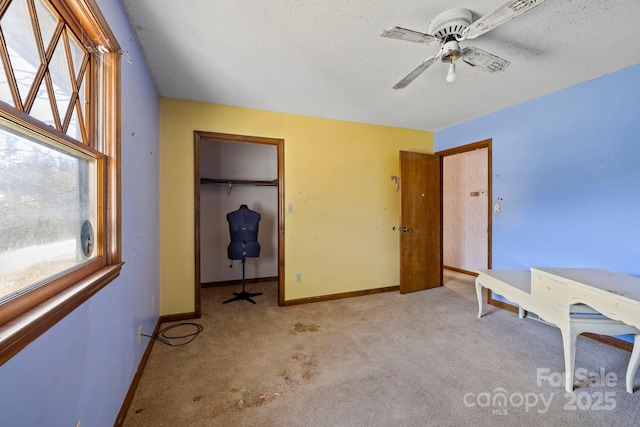 unfurnished bedroom with ceiling fan, light colored carpet, a textured ceiling, and a closet