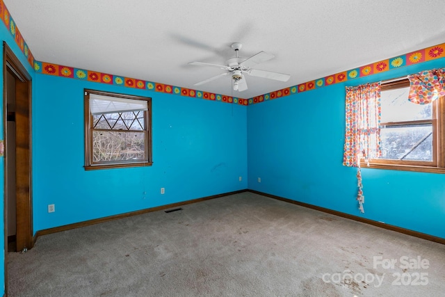 carpeted spare room featuring ceiling fan and a textured ceiling