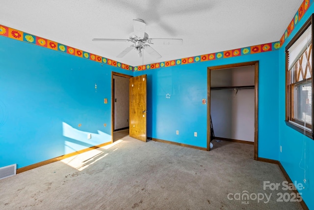 unfurnished bedroom featuring carpet flooring, ceiling fan, a textured ceiling, and a closet