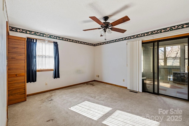 spare room featuring ceiling fan, light colored carpet, and a textured ceiling