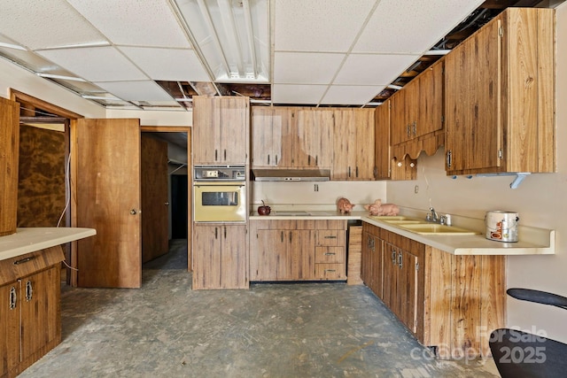 kitchen with cooktop, wall oven, a drop ceiling, and sink