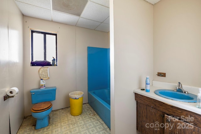 bathroom with a tub to relax in, a paneled ceiling, and vanity