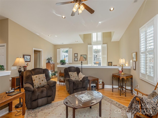 living room with ceiling fan, vaulted ceiling, and light wood-type flooring