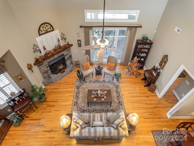 living room featuring a fireplace, a towering ceiling, hardwood / wood-style flooring, and a skylight