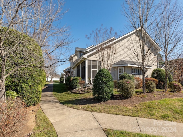 view of property exterior featuring a sunroom and a yard