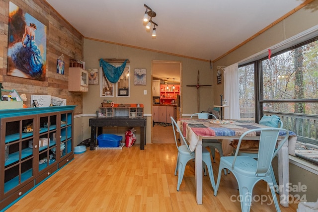 dining room with ornamental molding, lofted ceiling, light hardwood / wood-style flooring, and a healthy amount of sunlight