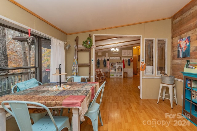 dining area featuring hardwood / wood-style floors, crown molding, wooden walls, vaulted ceiling, and a notable chandelier