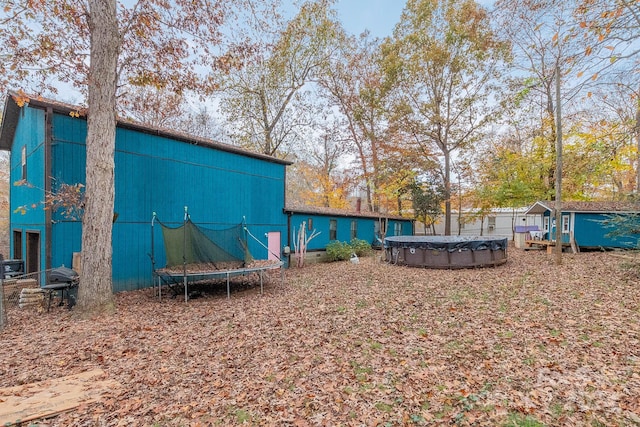 view of yard with a covered pool, a trampoline, and a storage unit