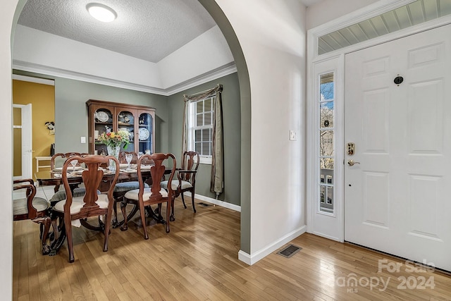 foyer featuring crown molding, a textured ceiling, and light wood-type flooring