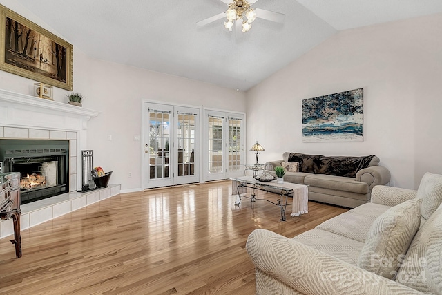 living room featuring a fireplace, wood-type flooring, vaulted ceiling, and ceiling fan