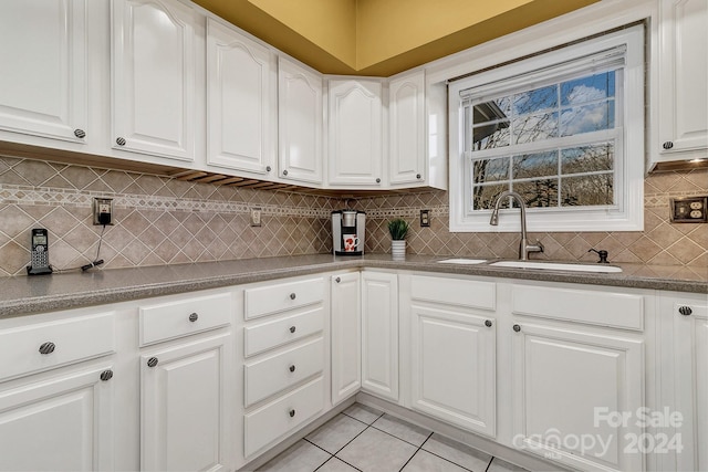 kitchen with tasteful backsplash, white cabinetry, and sink