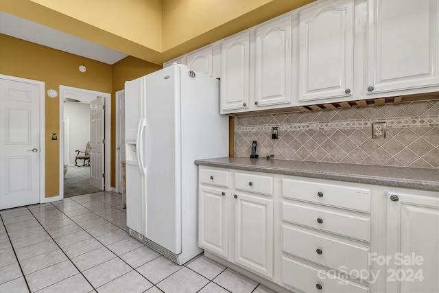 kitchen featuring white cabinetry, white fridge with ice dispenser, light tile patterned floors, and tasteful backsplash