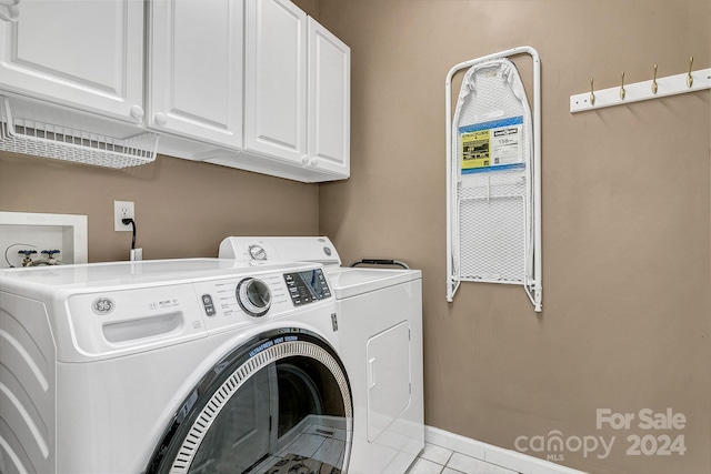 laundry room with light tile patterned flooring, cabinets, and washing machine and clothes dryer