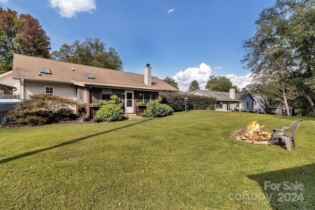 exterior space featuring an outdoor fire pit, a lawn, and a sunroom