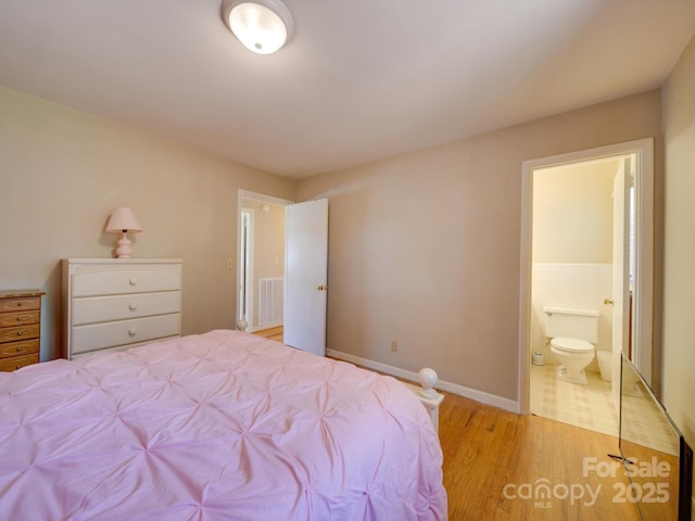 bedroom with ensuite bath and light hardwood / wood-style flooring