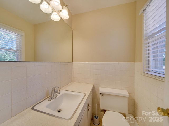 bathroom with tile walls, vanity, and toilet