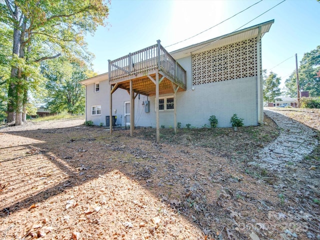 back of house featuring cooling unit and a wooden deck