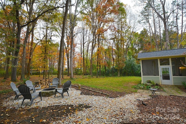 view of yard featuring a sunroom, an outdoor fire pit, and a patio