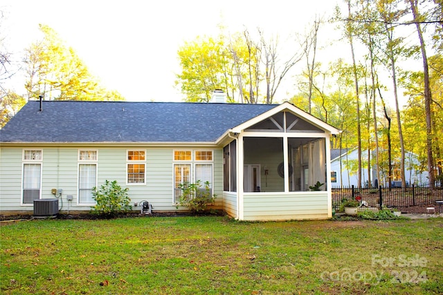 back of house with central air condition unit, a lawn, and a sunroom