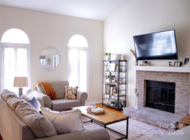 living room featuring a brick fireplace, a wealth of natural light, vaulted ceiling, and hardwood / wood-style flooring