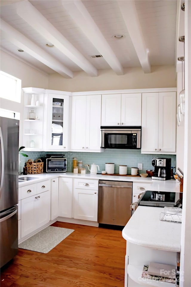 kitchen with stainless steel appliances, beamed ceiling, backsplash, light hardwood / wood-style floors, and white cabinets