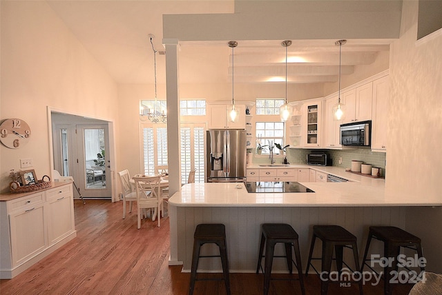 kitchen featuring white cabinetry, a kitchen breakfast bar, dark hardwood / wood-style flooring, kitchen peninsula, and appliances with stainless steel finishes