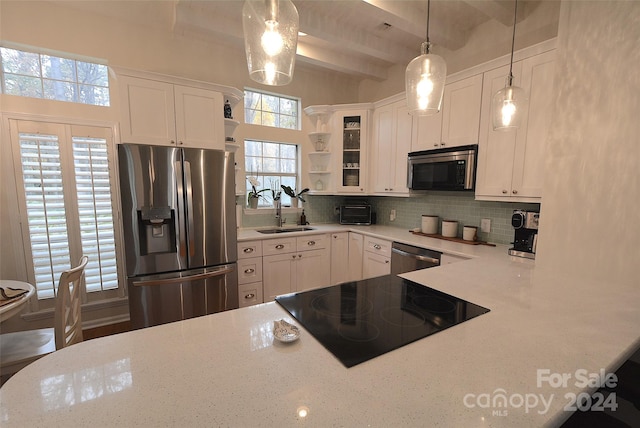 kitchen with beam ceiling, sink, stainless steel appliances, decorative light fixtures, and white cabinets