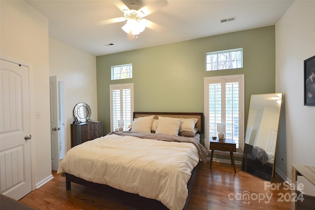 bedroom featuring dark hardwood / wood-style flooring, multiple windows, and ceiling fan