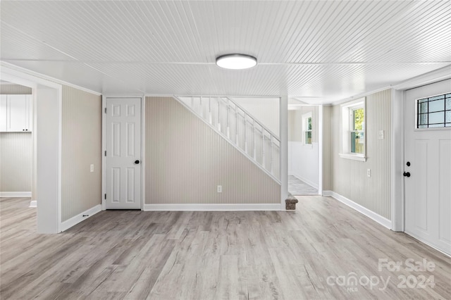 basement featuring wooden walls and light wood-type flooring