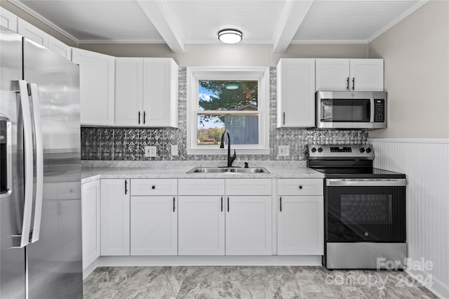 kitchen featuring beamed ceiling, appliances with stainless steel finishes, white cabinetry, and sink