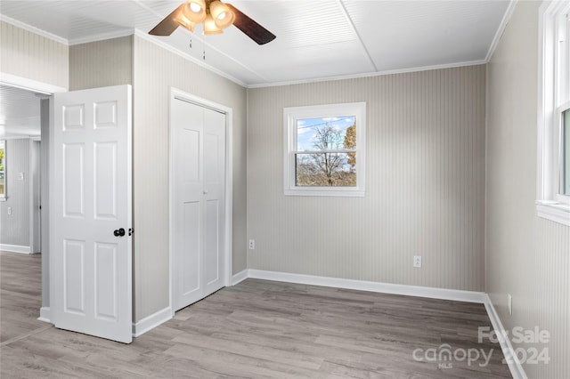 unfurnished bedroom with ceiling fan, a closet, ornamental molding, and light hardwood / wood-style flooring