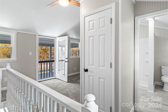 corridor featuring wood-type flooring, a wealth of natural light, ornamental molding, and wood walls