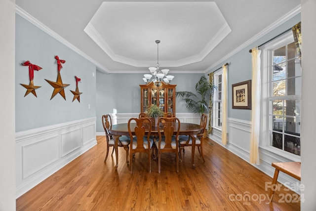 dining space with hardwood / wood-style flooring, a tray ceiling, and ornamental molding