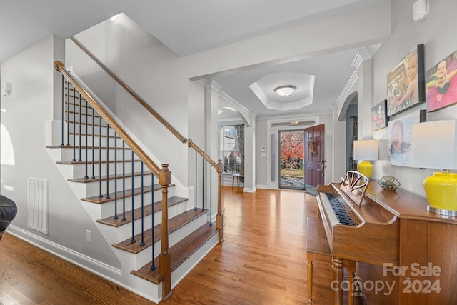 entrance foyer featuring a raised ceiling, crown molding, and light hardwood / wood-style flooring