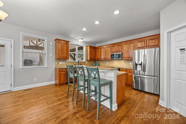 kitchen featuring a healthy amount of sunlight, a center island, stainless steel appliances, and light hardwood / wood-style floors