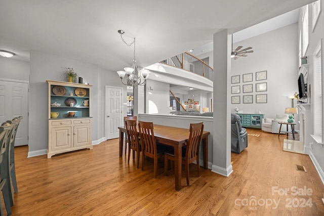 dining room featuring a high ceiling, ceiling fan with notable chandelier, and light hardwood / wood-style flooring