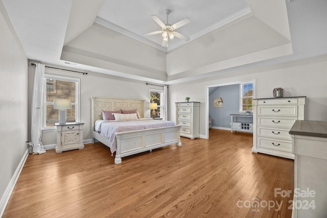 bedroom featuring a tray ceiling, ceiling fan, crown molding, and light hardwood / wood-style floors