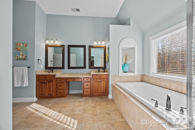 bathroom with tile patterned floors, a relaxing tiled tub, lofted ceiling, and vanity