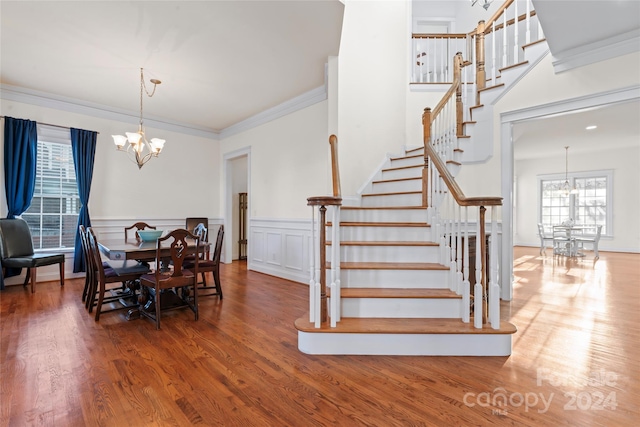 dining area with wood-type flooring, crown molding, and a notable chandelier