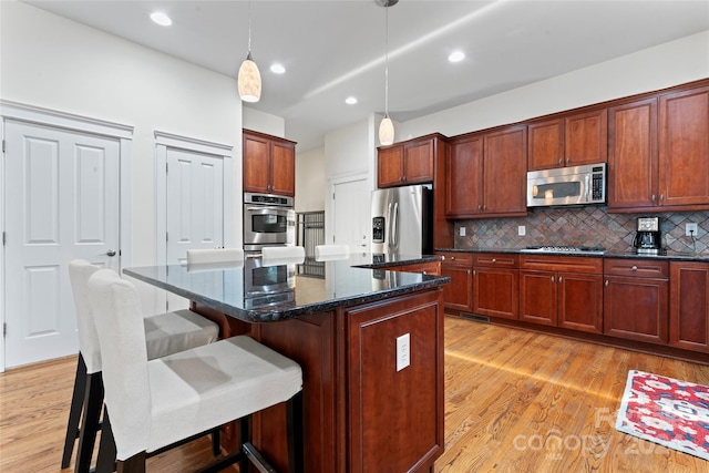 kitchen featuring stainless steel appliances, a kitchen island, and light hardwood / wood-style floors