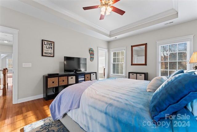 bedroom featuring hardwood / wood-style floors, a tray ceiling, ceiling fan, and ornamental molding