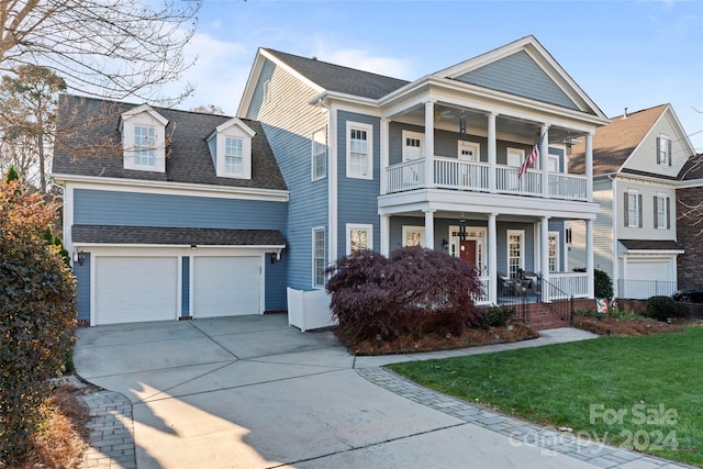 view of front of house featuring covered porch, a garage, a balcony, and a front lawn